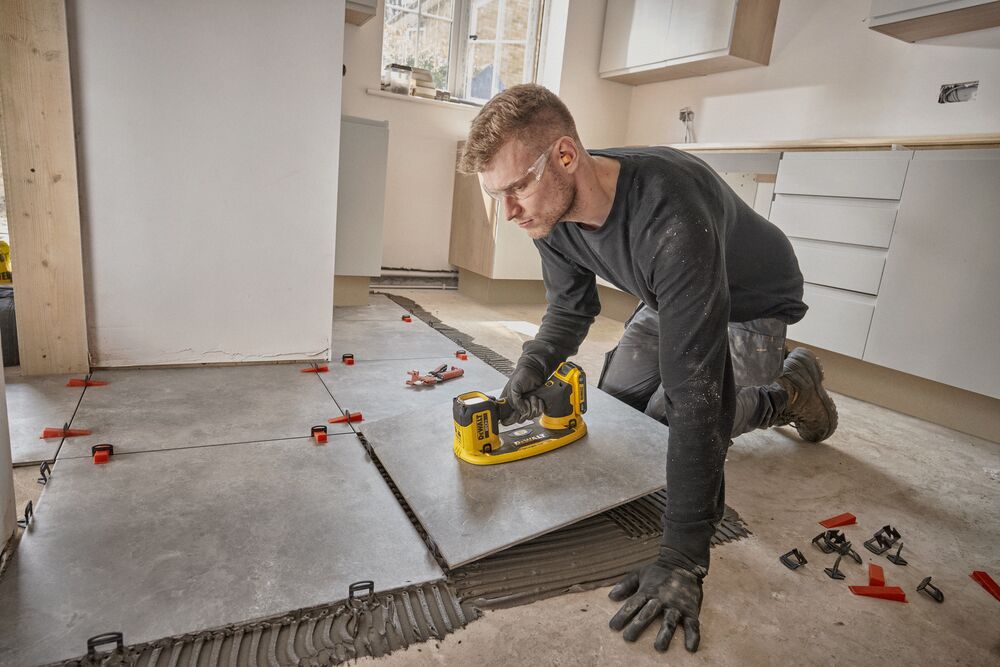 User installing tile flooring with DEWALT 20V MAX  Grabo Lifter 