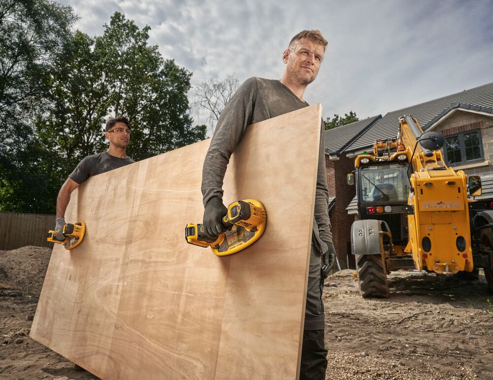 Two users carrying plywood with DEWALT 20V MAX Grabo Lifters on jobsite