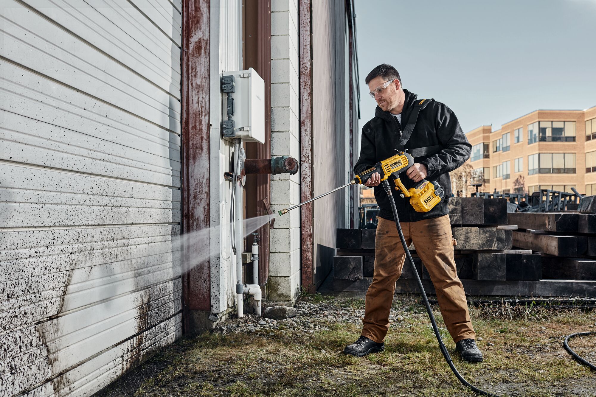 User cleaning siding with DEWALT 60V Power Cleaner
