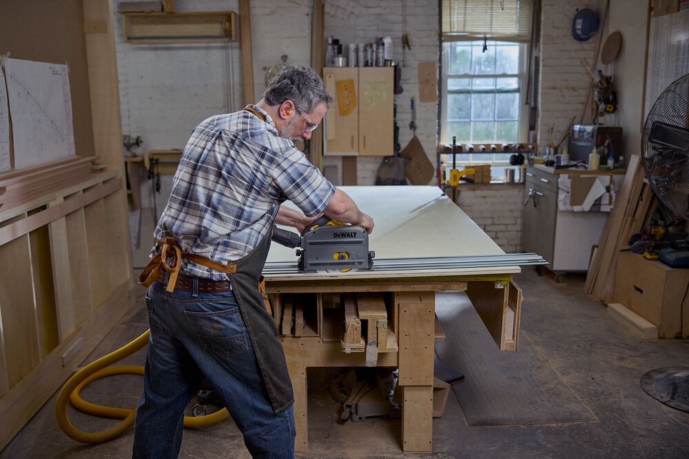 A carpenter uses a track saw with a dust shroud