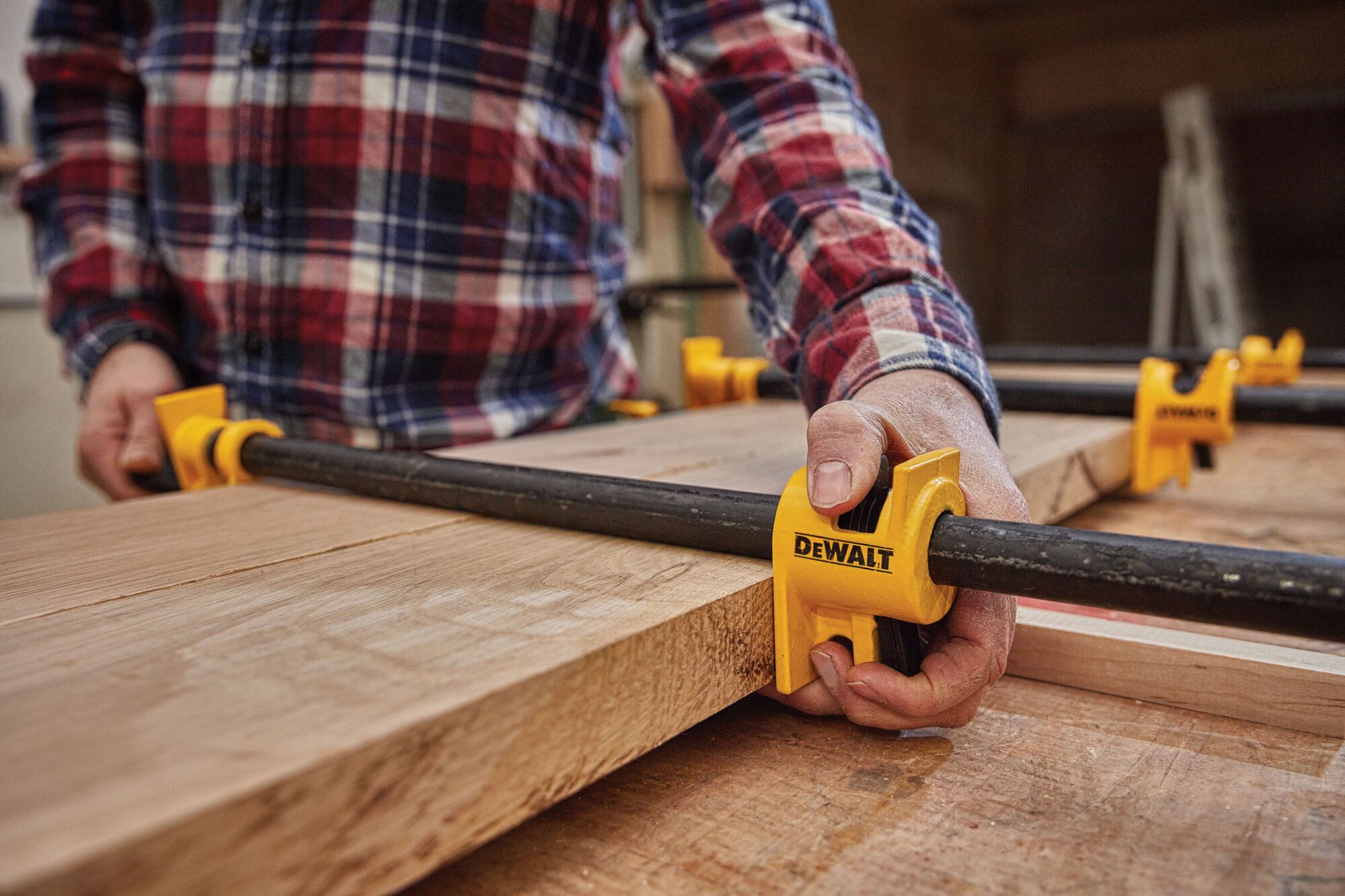 Close up of  half inch Pipe Clamp Fixture being used on a wooden structure by a person.