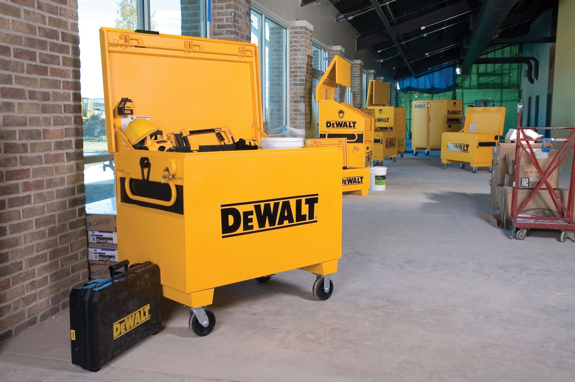 Multiple heavy duty jobsite storage chest filled with tools placed in a room.