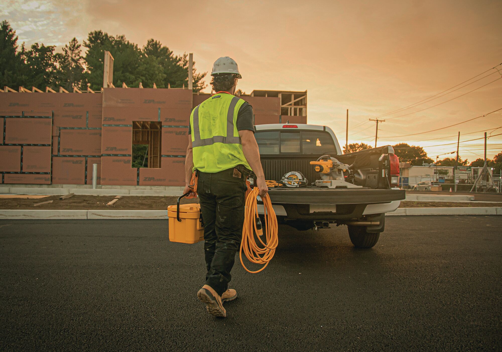 50 feet twelve thirds Lighted Locking C G M Extension Cord being carried by worker towards truck with tools.