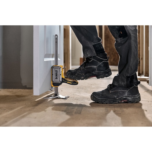 Worker lifting a door with DEWALT(R) TOUGHSERIES(TM) CONSTRUCTION JACK step to lift feature