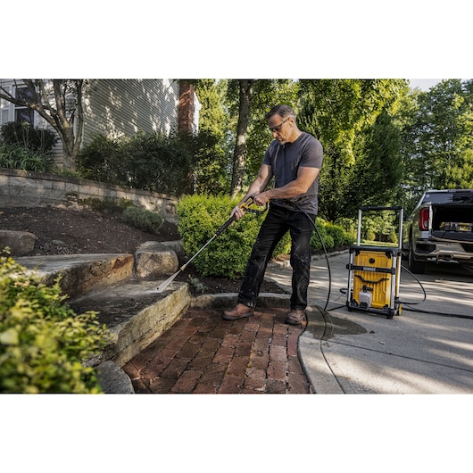 DEWALT 15 Amp Jobsite Electric Cold Water Pressure Washer being used by man to pressure wash stone steps at a home. 