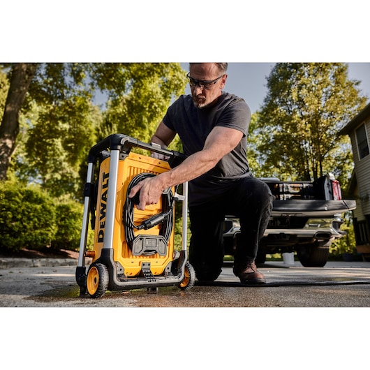 DEWALT 15 Amp Electric Cold Water Pressure Washer being pulled by a man in front of a truck parked in a driveway. 