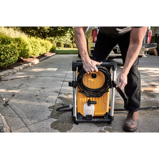 DEWALT 15 Amp Electric Cold Water Pressure Washer getting set up for use by a man in front of a truck parked in a driveway. 