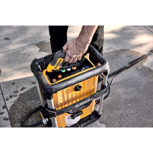 DEWALT 15 Amp Electric Cold Water Pressure Washer wand being pulled out of the pressure washer by a man in front of a house. 